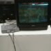 Una console PlayStation 1 è collegata a un televisore a tubo catodico che trasmette l’immagine di due lottatori che combattono in un videogioco della serie Tekken